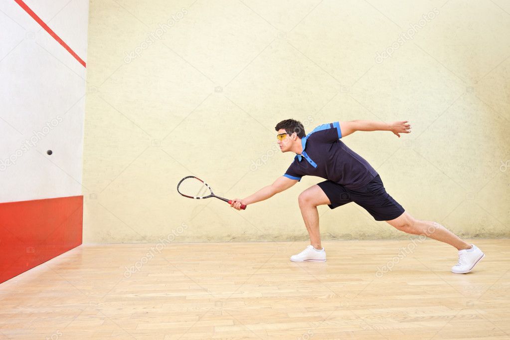 Squash player hiting ball
