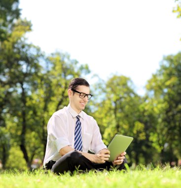 genç işadamı bir parkta bir tablet üzerinde çalışan