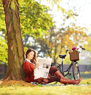 kadın bir gazete okuyor çimenlerin üzerinde