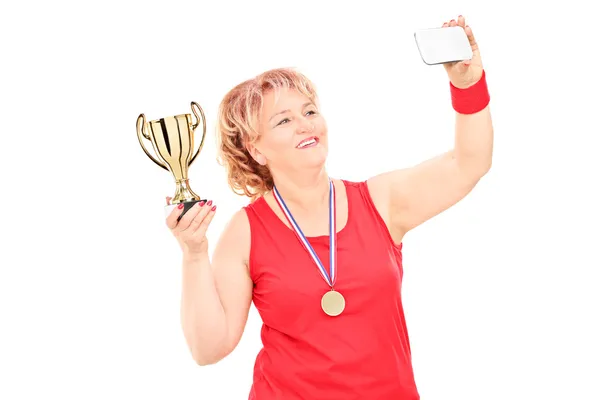 Mulher segurando troféu e tirando uma selfie — Fotografia de Stock