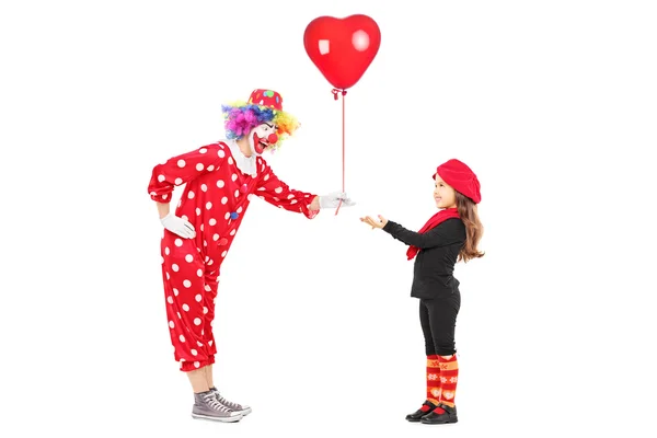 Male clown giving a red balloon to a little girl — Stock Photo, Image