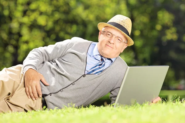 Starszy człowiek na trawie działa na laptopie — Zdjęcie stockowe