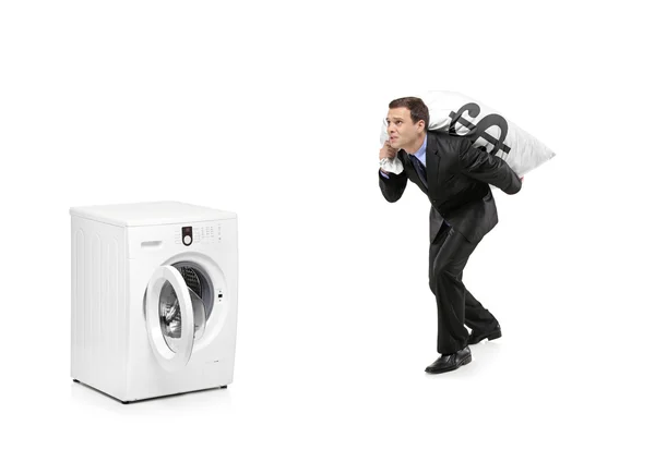 Man carrying a money bag and going towards a washing machine — Stock Photo, Image