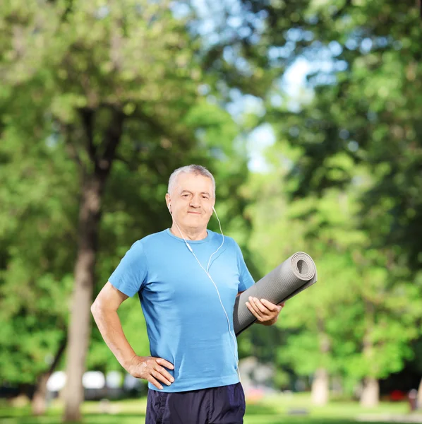 Mature man holding mat in park — Stock Photo, Image