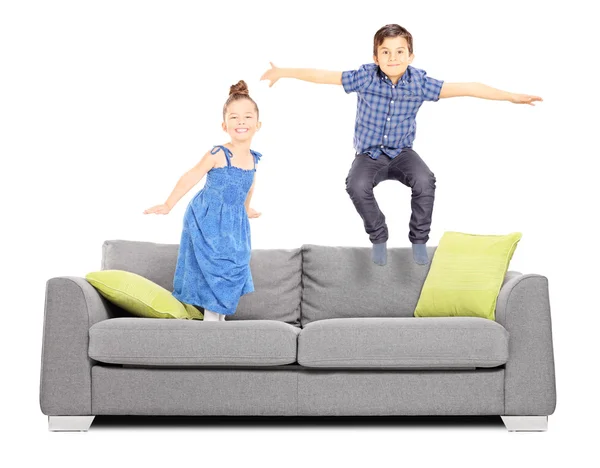 Pojke och flicka hoppa på soffan — Stockfoto