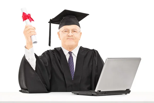 Mature man in graduation and laptop — Stock Photo, Image