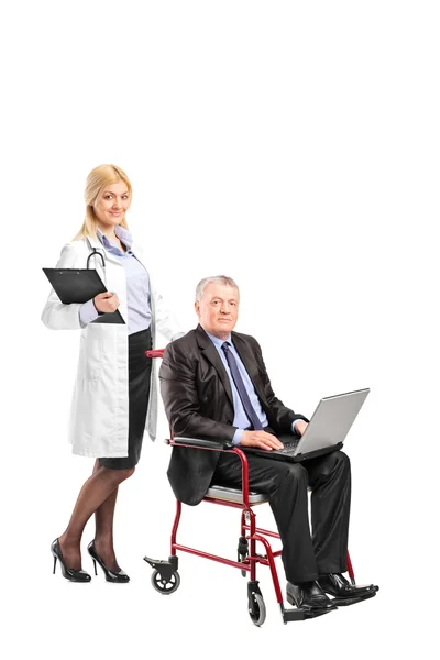 Nurse pushing businessman working on laptop — Stock Photo, Image