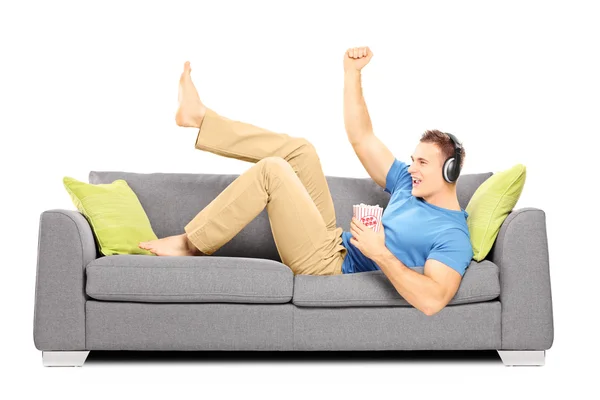 Guy lying on sofa and listening music — Stock Photo, Image