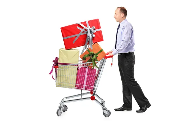 Homem empurrando carrinho de compras com presentes — Fotografia de Stock
