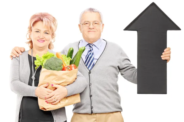 Couple holding groceries and arrow — Stock Photo, Image