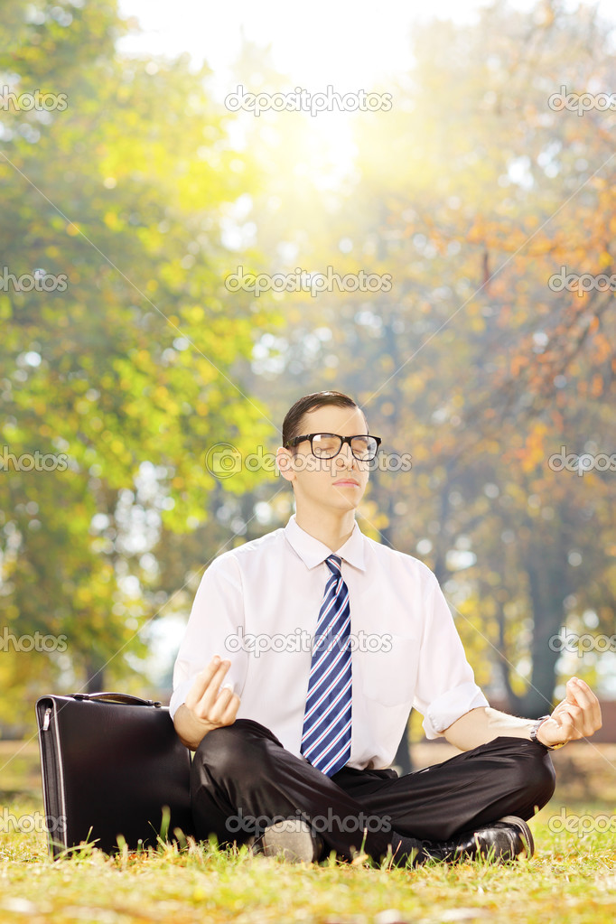 Businessperson meditating on a grass