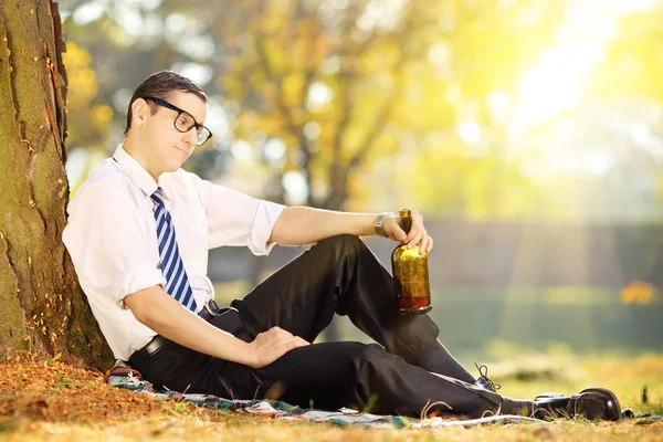 Homme d'affaires assis sur l'herbe avec bouteille — Photo