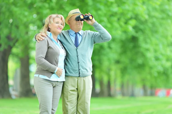 Senior couple looking through binoculars — Stock Photo, Image