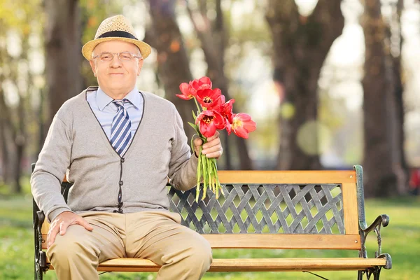 Senior man met rode tulpen — Stockfoto