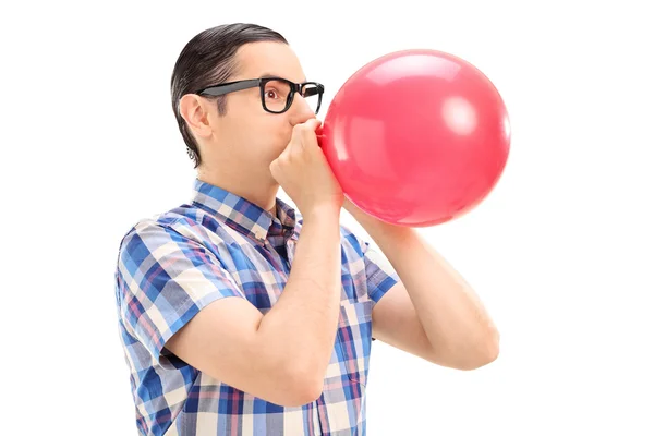 Young man blowing up balloon — Stock Photo, Image