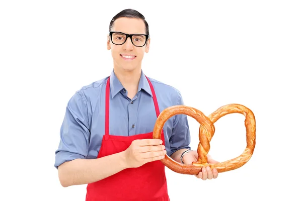 Чоловічий пекар тримає величезний крендель — стокове фото