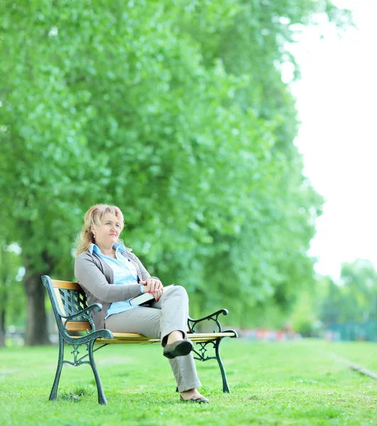 Érett nő ül a parkban — Stock Fotó