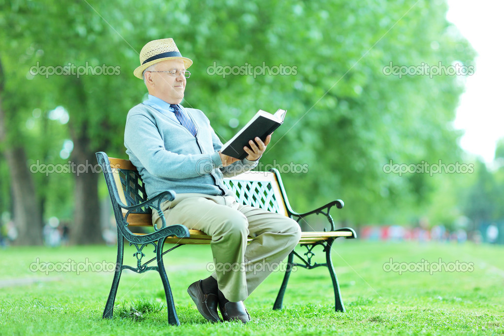 Anciano leyendo sentado en el banco — Foto de Stock