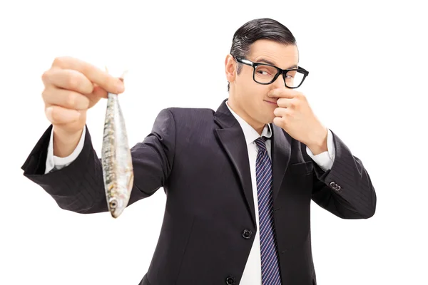 Young businessman holding stinky fish — Stock Photo, Image