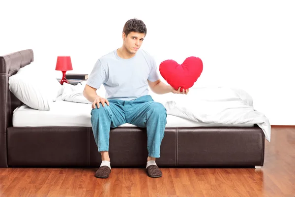 Guy on bed holding heart — Stock Photo, Image