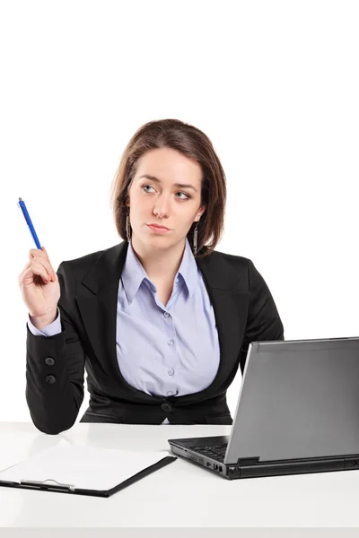 Businesswoman contemplating seated at desk Stock Picture