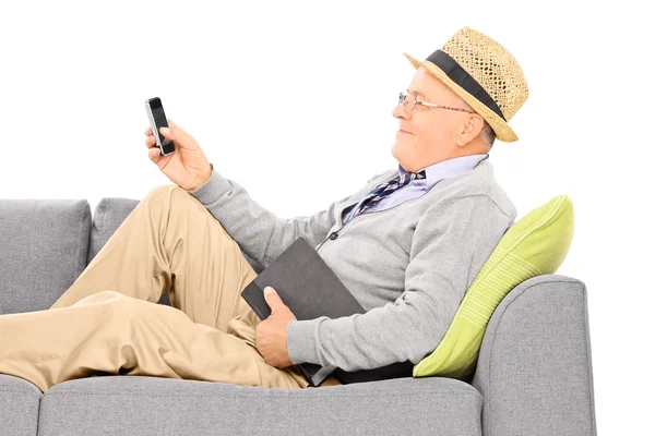 Sénior no sofá digitando sms — Fotografia de Stock