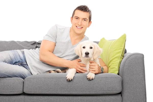 Человек на диване с щенком — стоковое фото