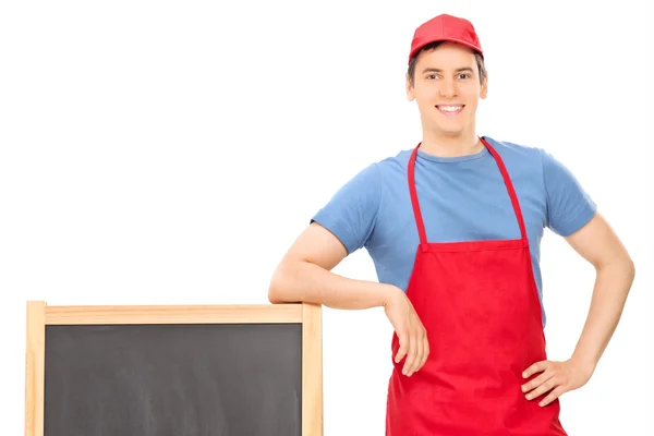 Young vendor standing by blackboard — Stock Photo, Image