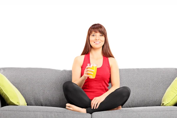 Woman drinking juice on sofa — Stock Photo, Image