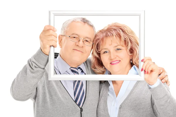 Mature couple behind picture frame — Stock Photo, Image