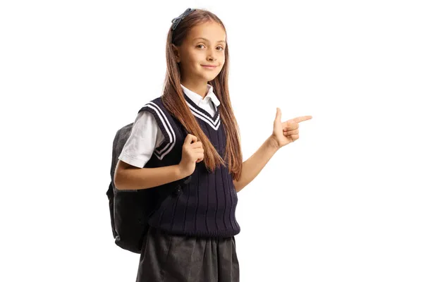 穿着背包和校服的女学生指着被白色背景隔开的侧面 — 图库照片