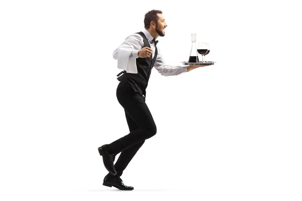 トレイにワインを運ぶウェイターの完全な長さプロファイルショットと白の背景に隔離された実行 — ストック写真