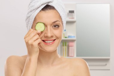 Banyoda genç bir kadın gözüne bir parça salatalık tutuyordu ve kafasına havlu geçirmişti.