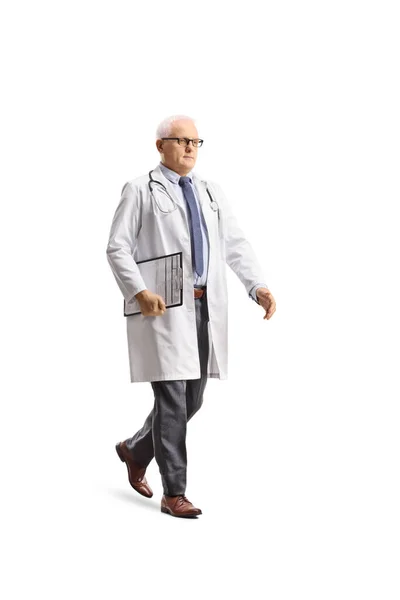 一个成熟的男医生拿着一块白色背景的剪贴板走路的全长照片 — 图库照片