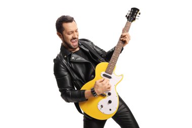 Deri ceketli ve pantolonlu genç bir müzisyen beyaz arka planda elektro gitar çalıyor. 