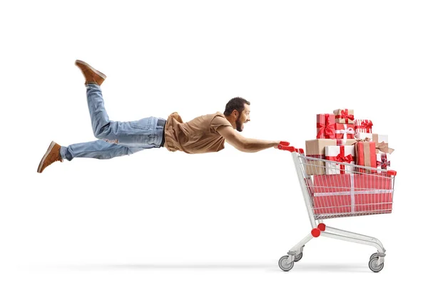 カジュアル男飛行と開催ショッピングカートフルのプレゼント隔離された白の背景 — ストック写真