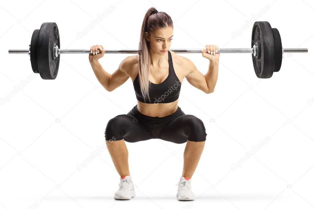 Fit young woman bodybuilder kneeling with heavy weights isolated on white background
