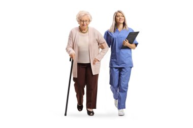 Mavi üniformalı genç bir kadın hemşirenin portresi beyaz arka planda izole edilmiş yaşlı bir kadın hastaya eşlik ediyor.