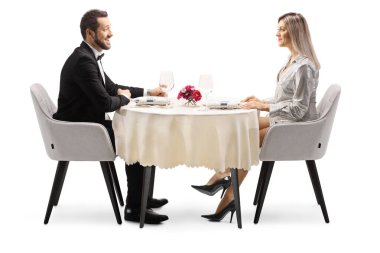 Genç, zarif bir adam ve kadın, beyaz arka planda, bir restoran masasında tek başlarına oturuyorlar.