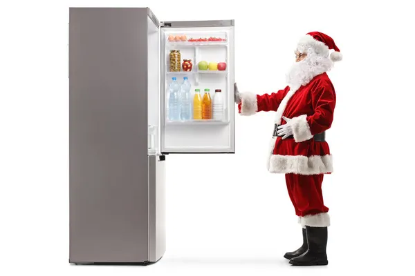 Ganzseitige Profilaufnahme Des Weihnachtsmannes Beim Öffnen Eines Kühlschranks Voller Lebensmittel — Stockfoto