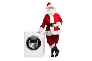 Noel Baba beyaz arka planda izole edilmiş çamaşır makinesine yaslanıyor.