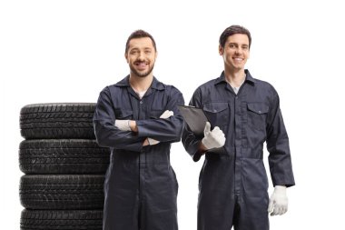 İki araba tamircisi üniformalı ve beyaz arka planda izole edilmiş araba lastikleri var.