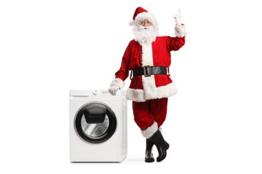 Noel Baba 'nın tam boy portresi çamaşır makinesine yaslanmış ve beyaz arka planda izole edilmiş. 