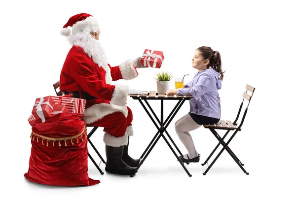 Święty Mikołaj Siedzi Przy Stole Daje Prezent Dziewczynie Odizolowanej Białym — Zdjęcie stockowe