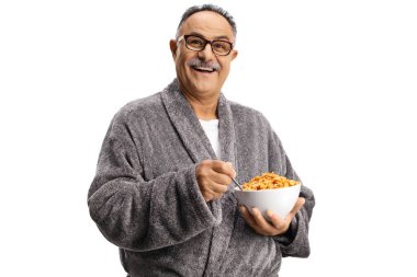 Bornozlu olgun bir adam beyaz arka planda izole bir kase mısır gevreği yiyor.