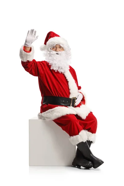 Santa Claus Sedí Bílé Kostce Mává Kameru Izolované Bílém Pozadí — Stock fotografie