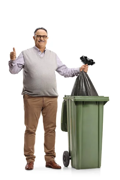 남자가 쓰레기통에 비닐봉지를 배경에 외따로 떨어져 엄지손가락을 — 스톡 사진