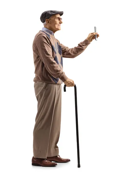 一个祖父拿着手杖站在那里 拿着一部白色背景的智能手机 照片全长 — 图库照片