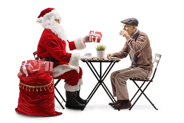 Święty Mikołaj Daje Prezent Starszemu Mężczyźnie Siedzi Przy Stole Odizolowany — Zdjęcie stockowe