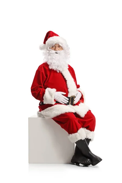 Santa Claus Sitter Vit Kub Och Tittar Kameran Isolerad Vit — Stockfoto